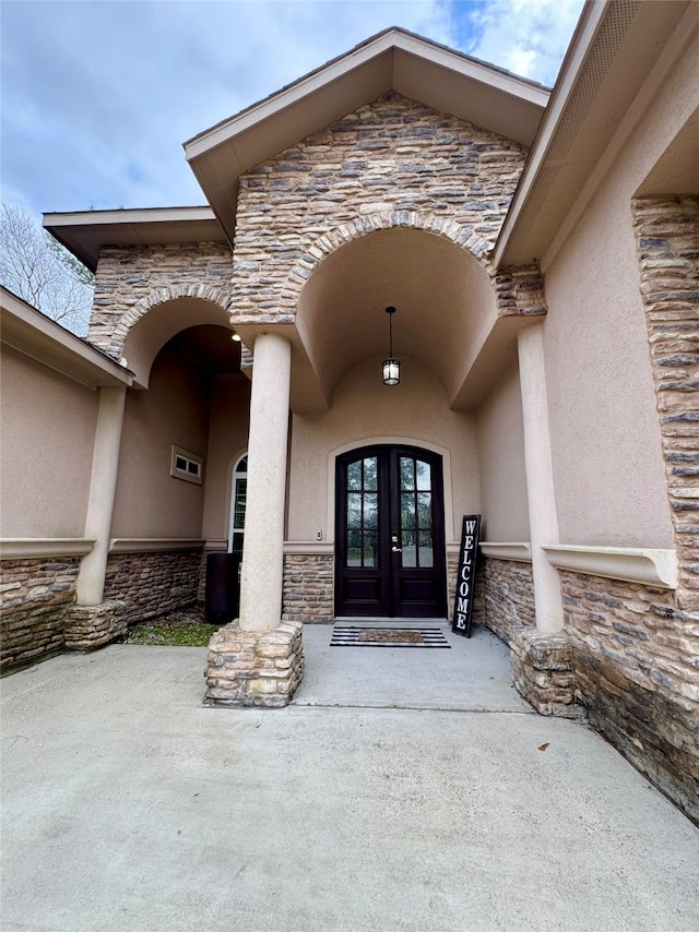 doorway to property featuring french doors, stone siding, and stucco siding