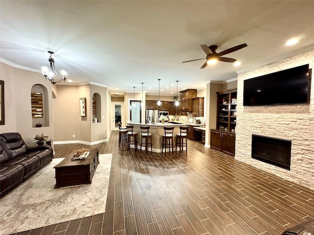 18315 Wisp Willow Way, Porter, TX 77365 - living area featuring ornamental molding, a fireplace, wood tiled floor, and ceiling fan with notable chandelier