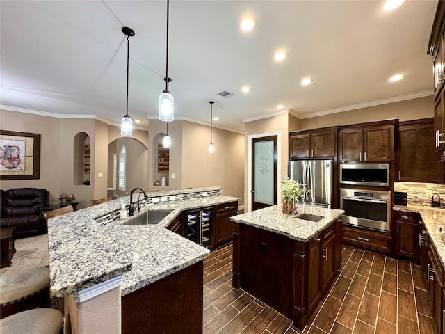 18315 Wisp Willow Way, Porter, TX 77365 - kitchen with visible vents, arched walkways, a sink, a large island, and appliances with stainless steel finishes