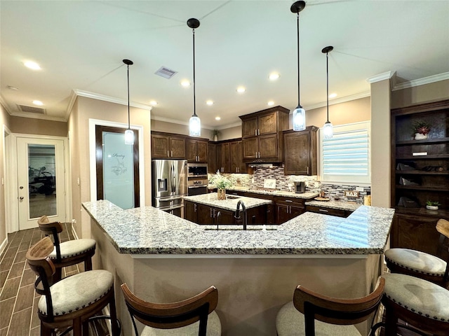 18315 Wisp Willow Way, Porter, TX 77365 - kitchen with visible vents, a sink, stainless steel appliances, a large island, and dark brown cabinets