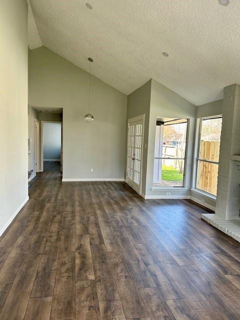 unfurnished living room with a textured ceiling, baseboards, vaulted ceiling, and dark wood finished floors