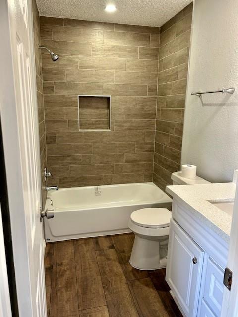 full bathroom featuring a textured ceiling, toilet, wood finished floors, vanity, and  shower combination