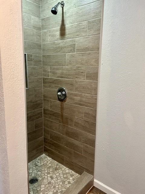 full bath featuring a stall shower and baseboards