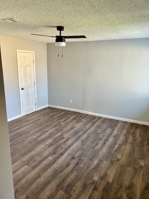 empty room featuring a ceiling fan, dark wood finished floors, a textured ceiling, and baseboards