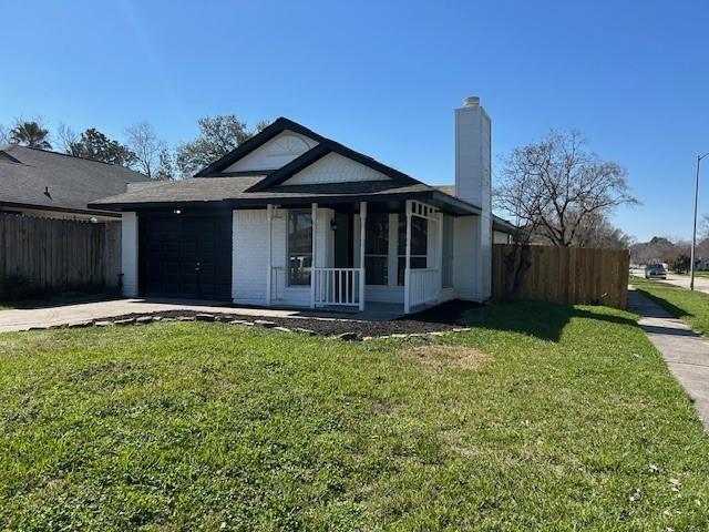 view of front of house featuring an attached garage, fence, driveway, a chimney, and a front yard