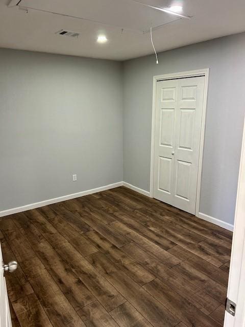 interior space featuring dark wood-style floors, attic access, visible vents, and baseboards