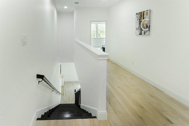 stairway featuring wood finished floors, visible vents, and baseboards