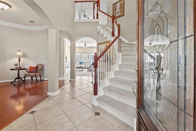 foyer entrance with stairs, arched walkways, ornamental molding, and light tile patterned flooring