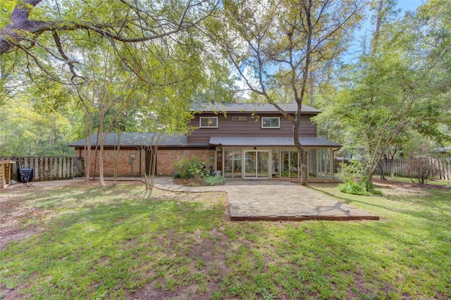 rear view of property with a patio area, a lawn, brick siding, and a fenced backyard