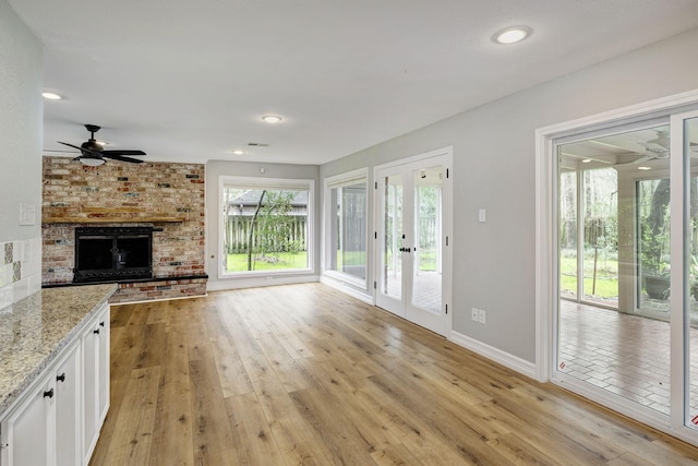 unfurnished living room featuring baseboards, a ceiling fan, a fireplace, and light wood finished floors