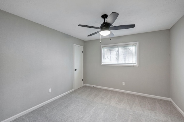 empty room featuring a ceiling fan, light colored carpet, and baseboards