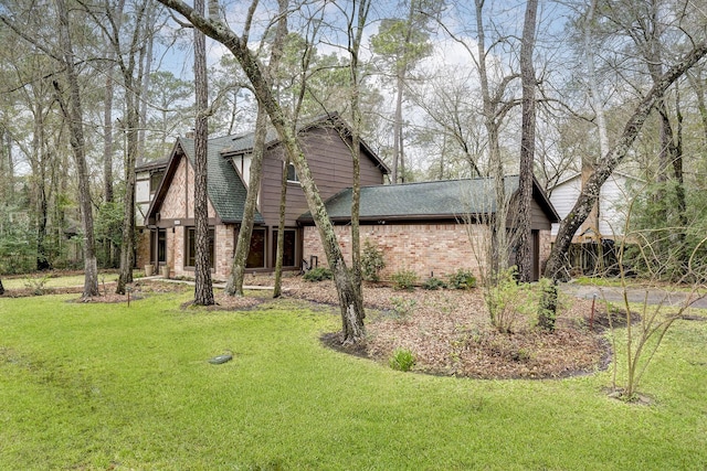 exterior space featuring a front yard, brick siding, and roof with shingles