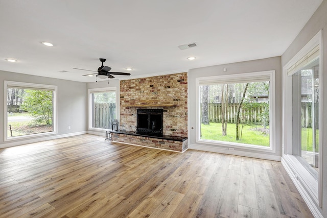 unfurnished living room with light wood finished floors, visible vents, a brick fireplace, baseboards, and recessed lighting