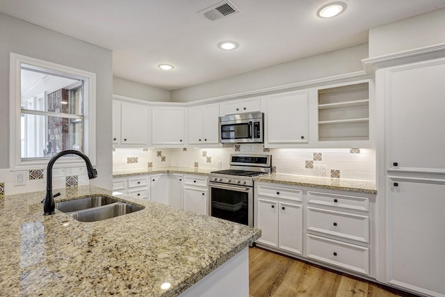 kitchen with visible vents, a sink, open shelves, stainless steel appliances, and white cabinets