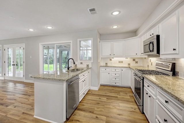 kitchen with visible vents, a sink, stainless steel appliances, light wood-style floors, and a peninsula