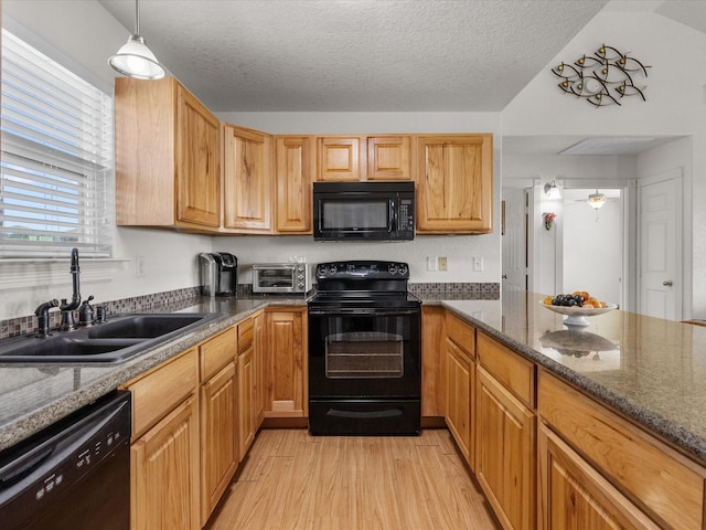 1206 Middle Dr W, Surfside Beach, TX 77541 - kitchen with black appliances, light wood-style floors, a textured ceiling, dark stone counters, and hanging light fixtures