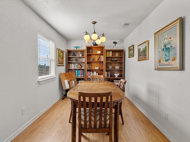 1206 Middle Dr W, Surfside Beach, TX 77541 - dining area featuring a chandelier, light wood finished floors, and a textured ceiling