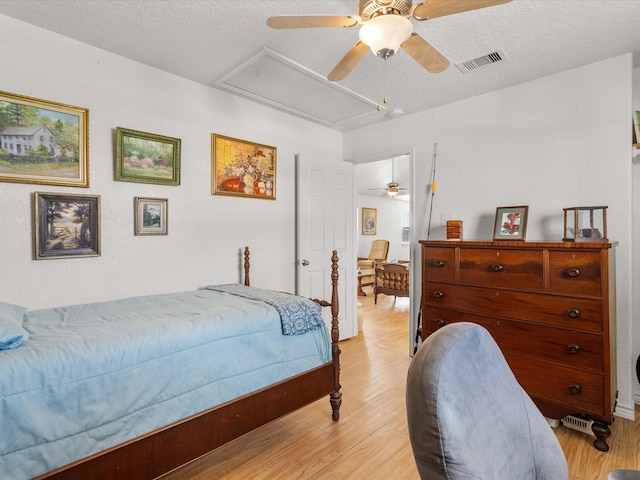 1206 Middle Dr W, Surfside Beach, TX 77541 - bedroom with light wood finished floors, ceiling fan, a textured ceiling, and attic access