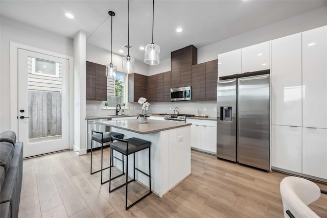 kitchen with appliances with stainless steel finishes, light wood-style flooring, a kitchen breakfast bar, and modern cabinets