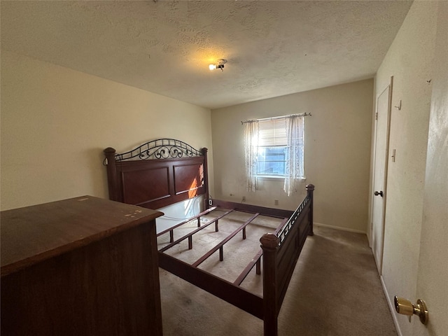 bedroom featuring dark carpet, a textured ceiling, and baseboards