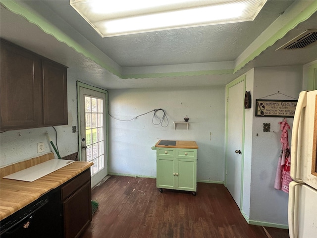 kitchen with butcher block counters, visible vents, dark wood-type flooring, freestanding refrigerator, and a textured ceiling