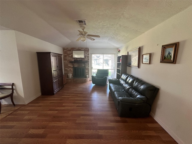 living room with lofted ceiling, a large fireplace, dark wood finished floors, and a textured ceiling