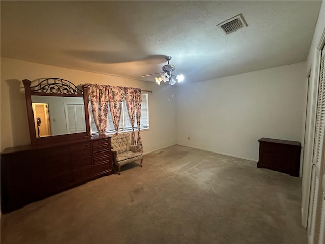 unfurnished room with carpet floors, a textured ceiling, visible vents, and a ceiling fan