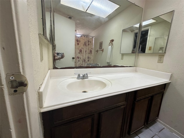 bathroom with curtained shower, a skylight, tile patterned flooring, and vanity