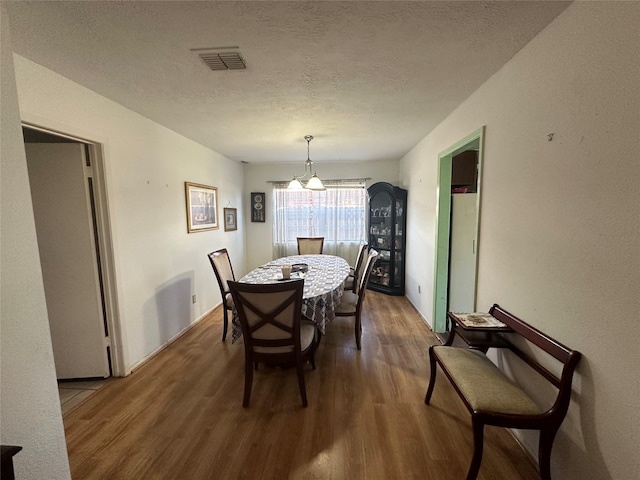 dining space featuring dark wood-style flooring, visible vents, and a textured ceiling