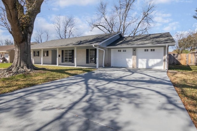 ranch-style home with brick siding, concrete driveway, a garage, and fence