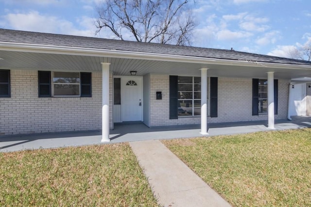 view of front of home featuring brick siding, a porch, and a front yard