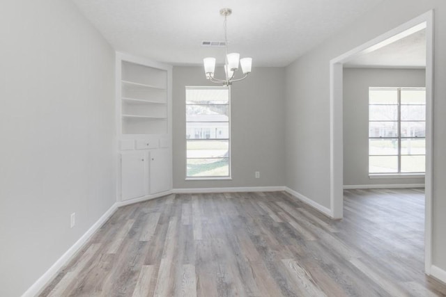 unfurnished dining area with wood finished floors, baseboards, and visible vents