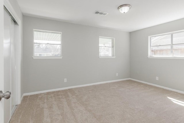spare room featuring baseboards, visible vents, and carpet floors