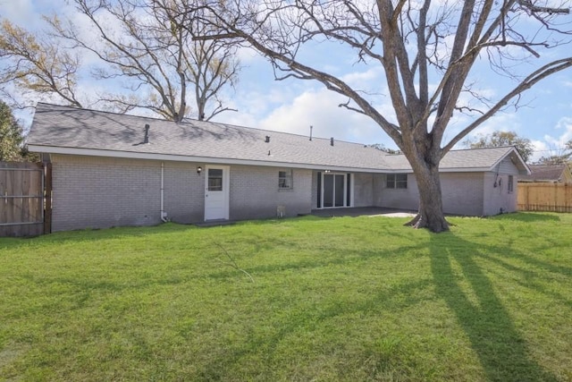 rear view of house featuring a patio area, a yard, fence, and brick siding