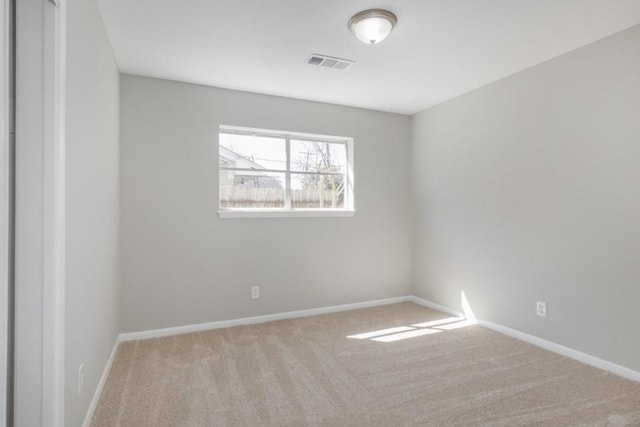 spare room featuring carpet, visible vents, and baseboards