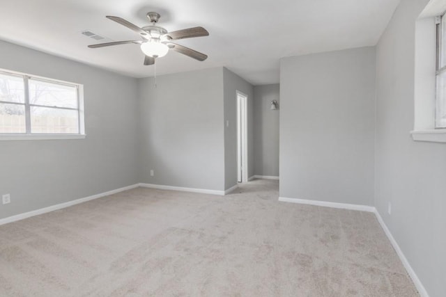 unfurnished room with visible vents, baseboards, light colored carpet, and a ceiling fan