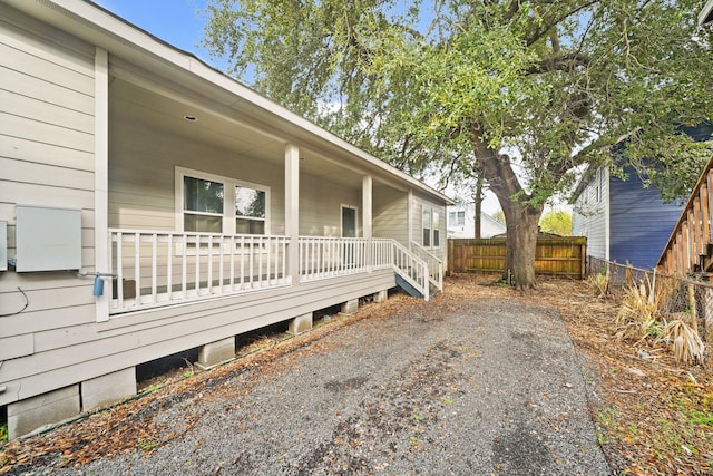 view of side of property featuring covered porch and fence