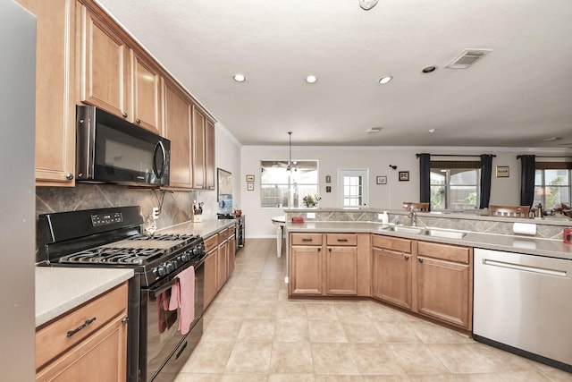 kitchen with pendant lighting, light countertops, decorative backsplash, a sink, and black appliances