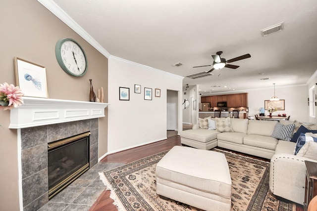 living room featuring a tile fireplace, visible vents, and ornamental molding