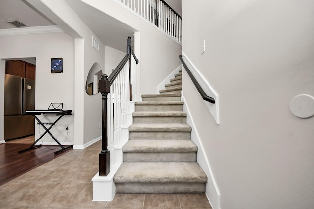 staircase featuring crown molding, wood finished floors, visible vents, and baseboards