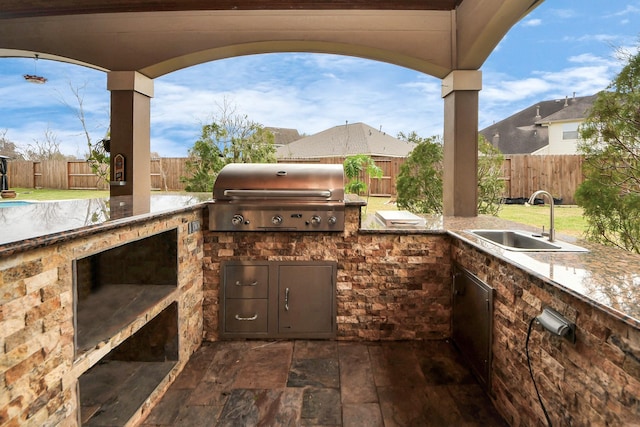 view of patio / terrace featuring exterior kitchen, a fenced backyard, a sink, and area for grilling