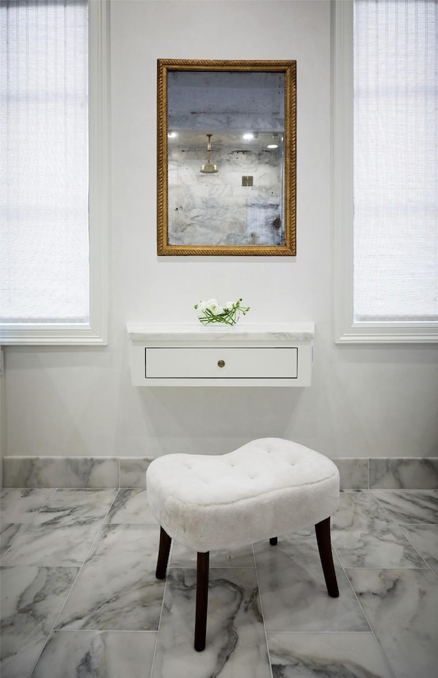 bathroom with a healthy amount of sunlight, marble finish floor, and a shower