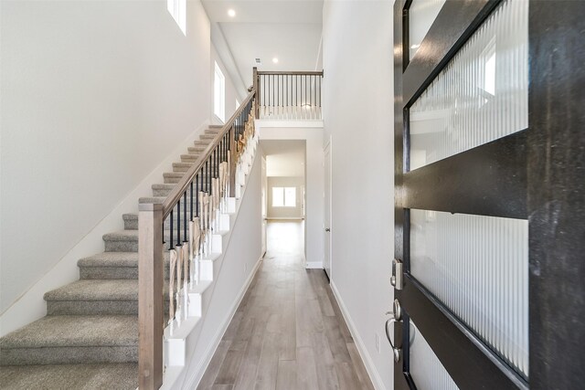 16319 Placid Stream St, Conroe, TX 77302 - corridor featuring wood finished floors, stairway, baseboards, a towering ceiling, and recessed lighting