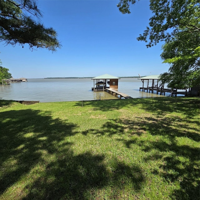 view of dock with a lawn, boat lift, and a water view
