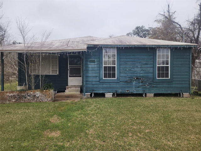 rear view of house with entry steps, central air condition unit, and a yard