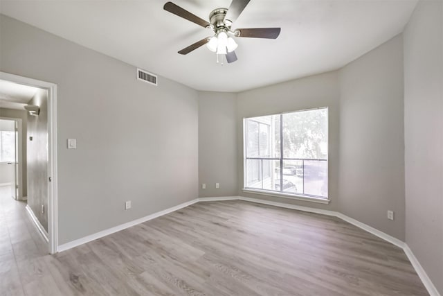 spare room featuring a ceiling fan, visible vents, light wood-style flooring, and baseboards