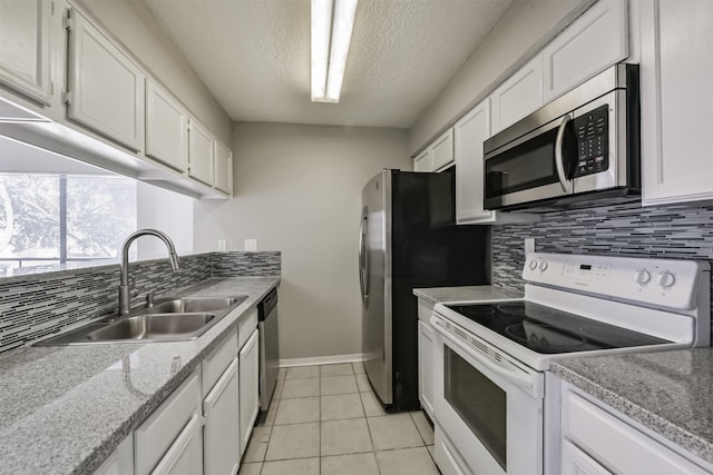 kitchen with light tile patterned floors, white cabinets, a sink, stainless steel appliances, and backsplash