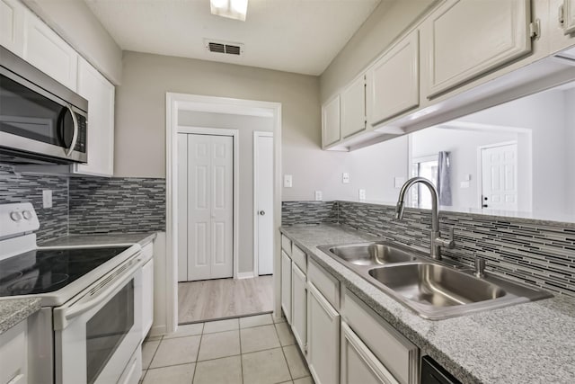 kitchen featuring visible vents, stainless steel microwave, electric range, white cabinets, and a sink