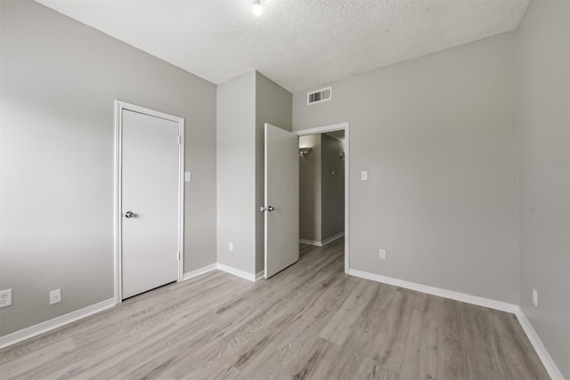 unfurnished bedroom with light wood-style floors, visible vents, a textured ceiling, and baseboards