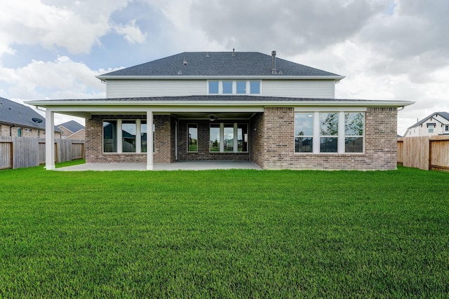 rear view of house with a shingled roof, a lawn, a patio, a fenced backyard, and brick siding